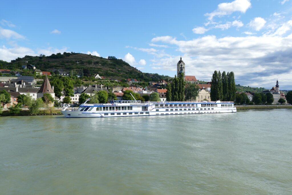 River cruise ship sailing along a European river past a historic town